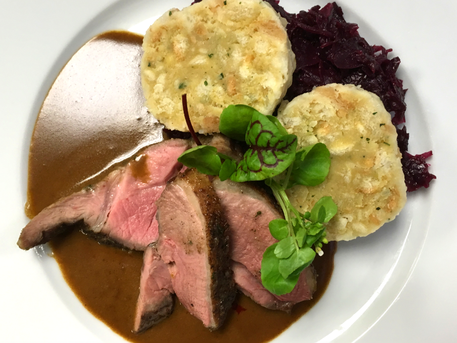 Stücke Fleisch mit Kartoffeltalern und Rotkohl